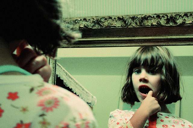 Little Girl is Looking at Her Mouth by Mirror