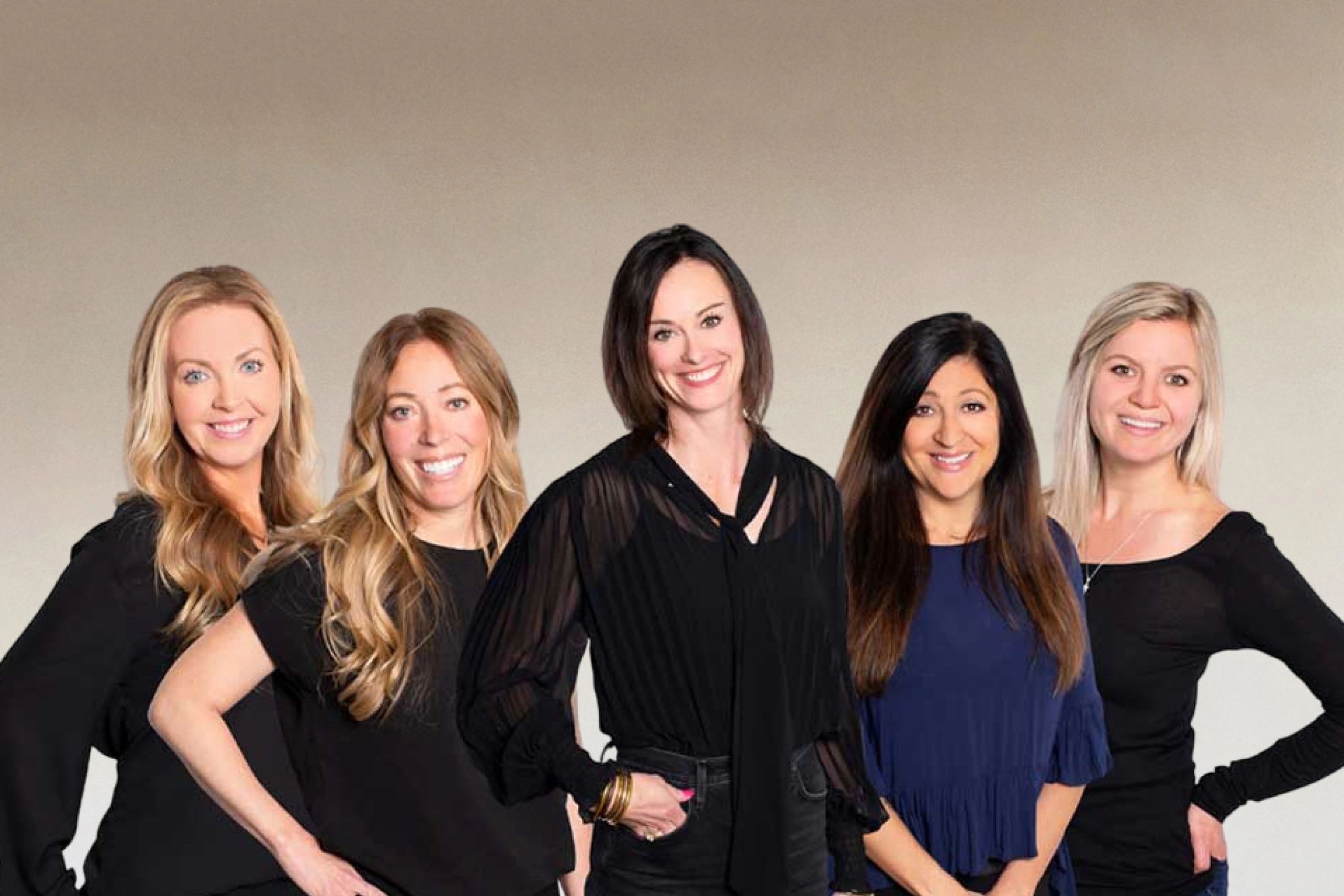 Five female dental professionals in dark clothing posing together against neutral background.