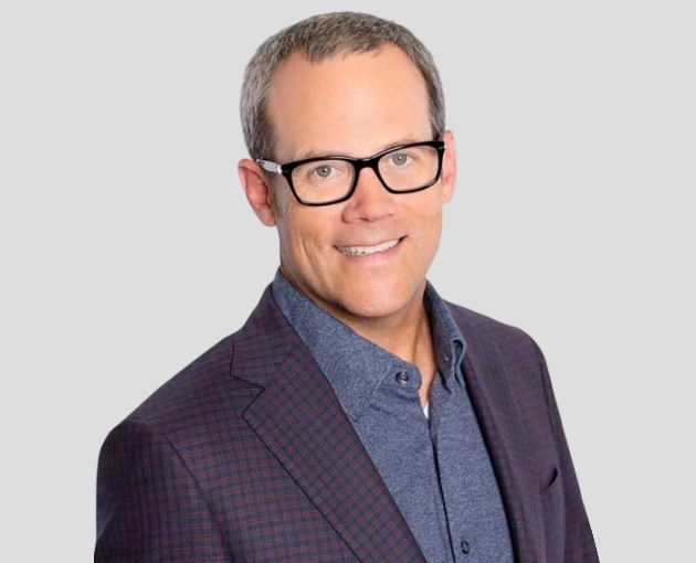 Professional man wearing glasses and blazer in headshot portrait for dental practice.