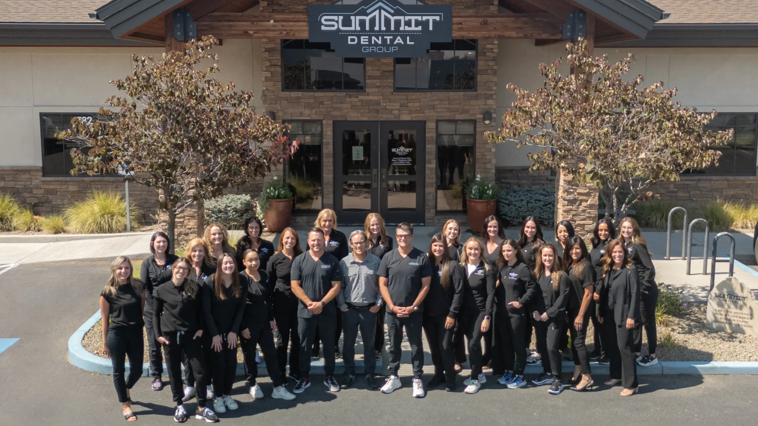 Summit Dental Group team posing together outside their dental office building entrance.