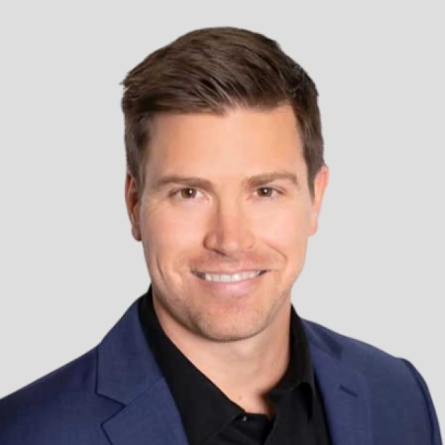 Professional headshot of male dental professional wearing navy blazer against neutral background.